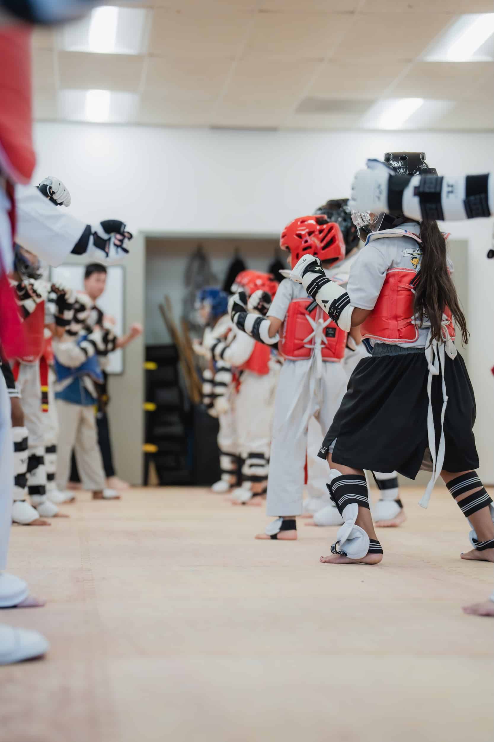 King's Martial Arts students wearing Taekwondo sparring gear getting ready for class.