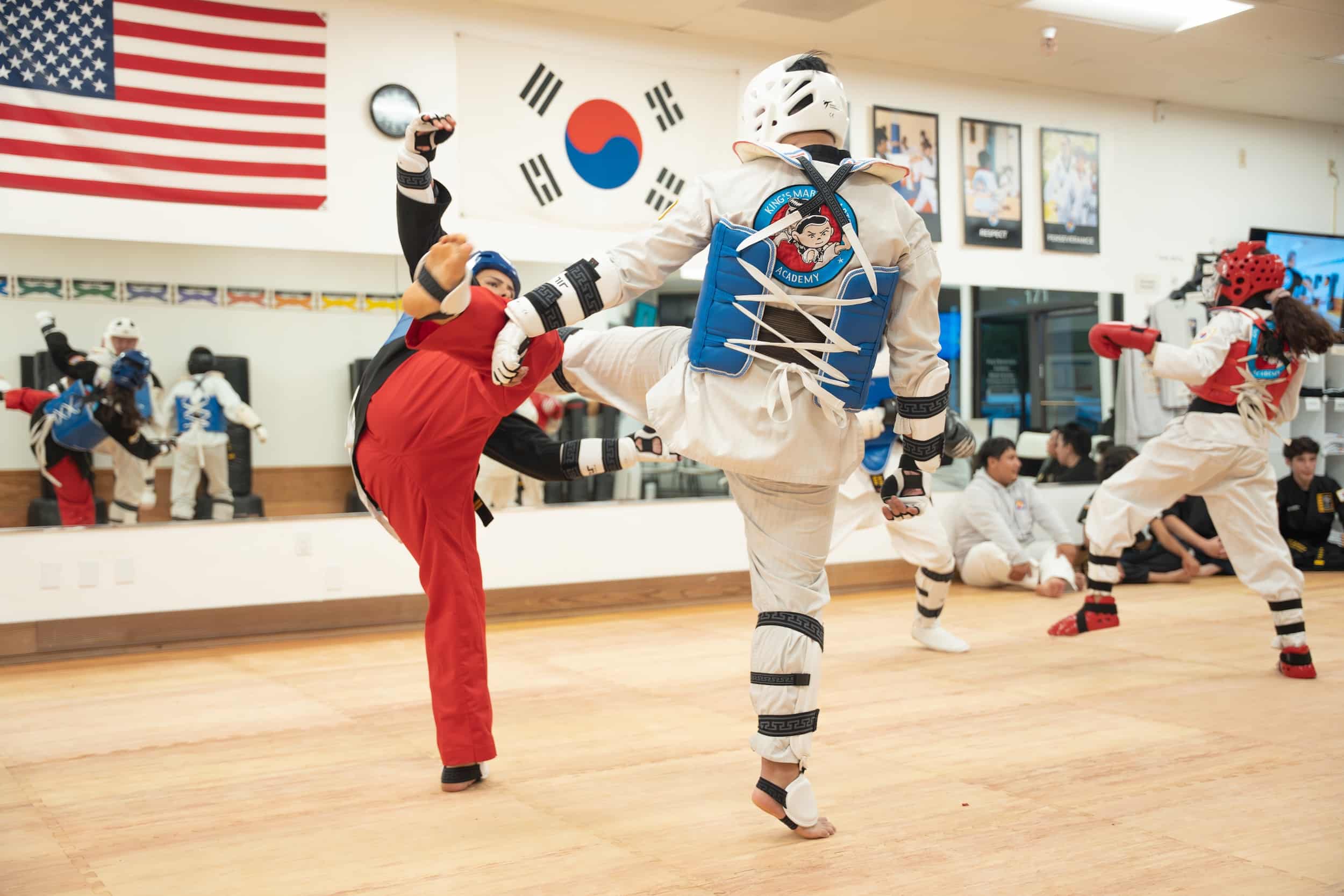 King's Martial Arts students sparring wearing Taekwondo protective gear during class.