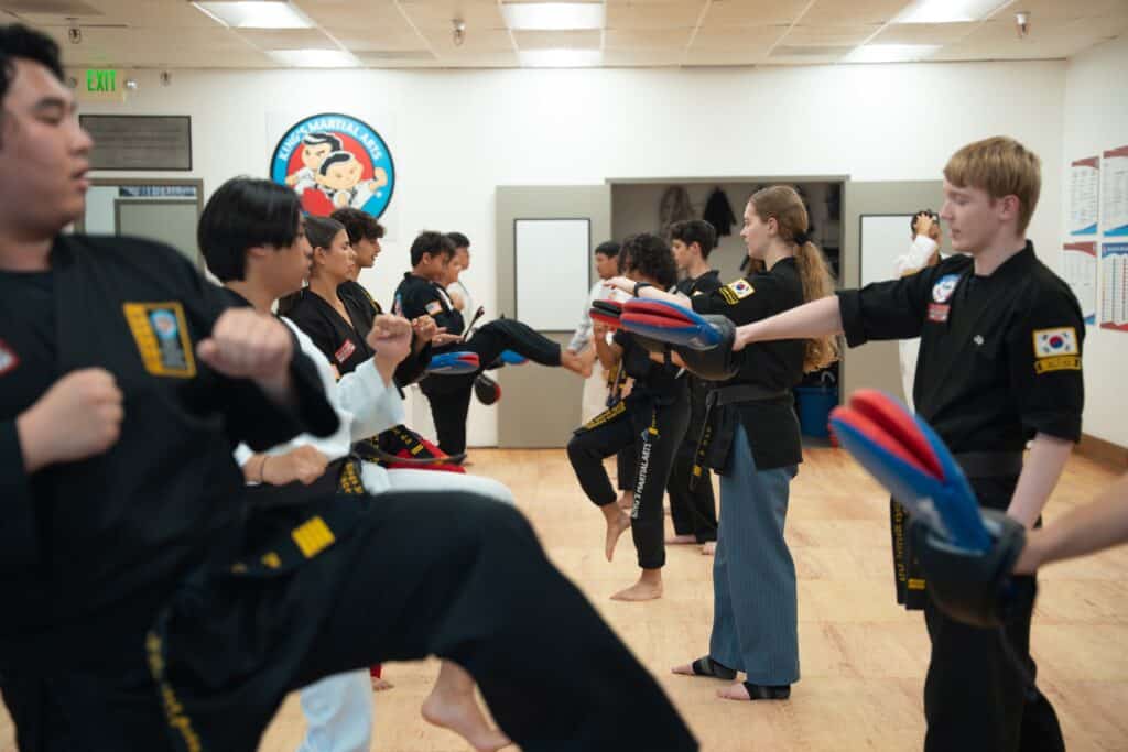 King's Martial Arts Academy Black Belt students practicing proper Taekwondo form wearing gi uniforms.